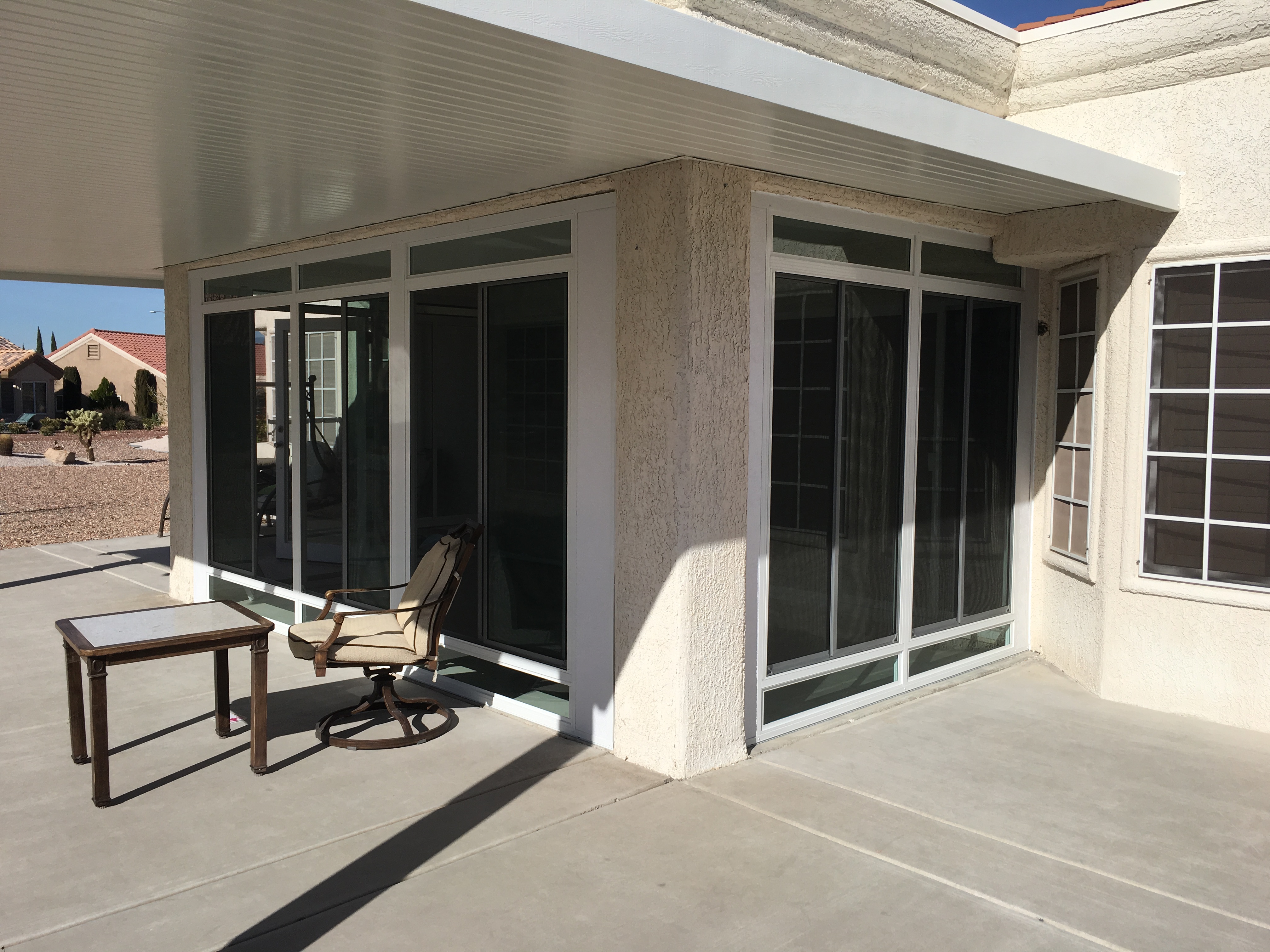 A custom sunroom with an extended roof and a stucco finish atop a poured concrete patio.