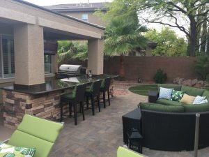 Picture of a backyard with an outdoor kitchen and stylish patio furniture.