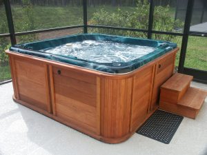 A hot tub with wood sides inside a screen room